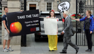 Uplift campaigners standing outside Leinster House with banner sayind Take the Tax